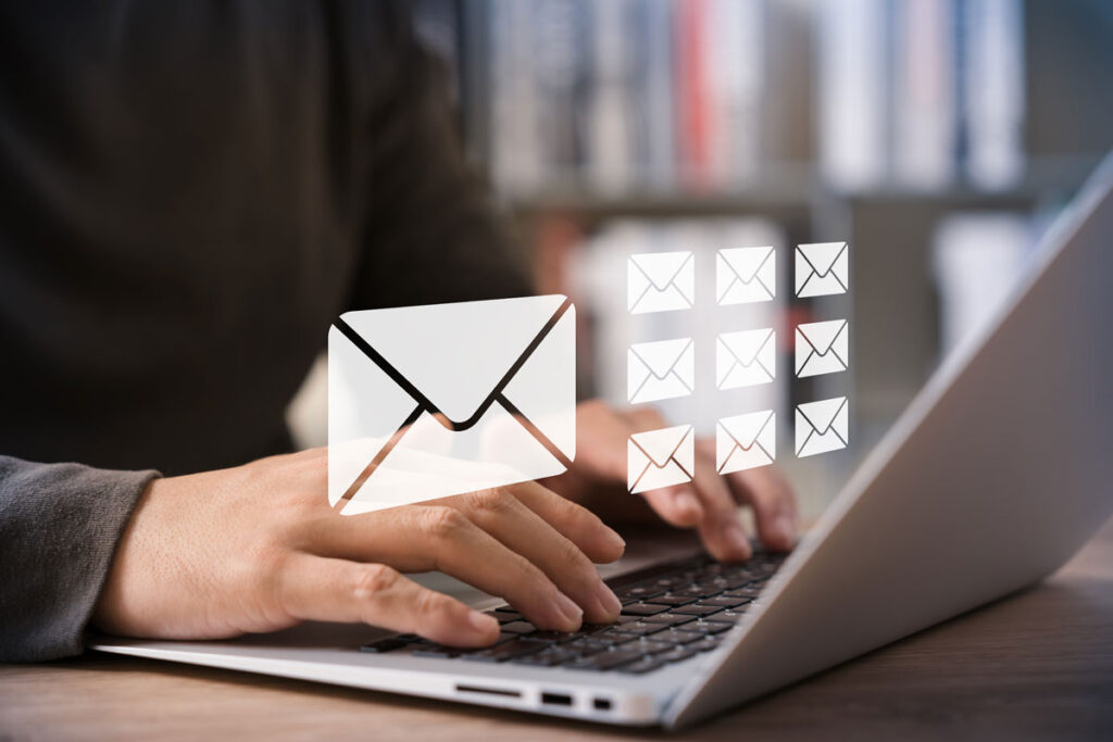 manos escribiendo en portátil con icono de Email flotante