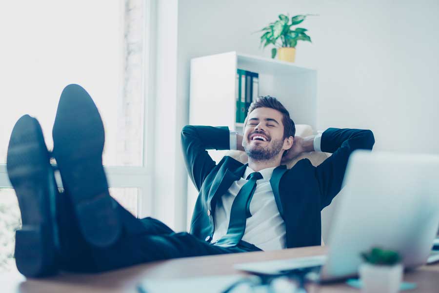 Hombre despreocupado y riendo con los pies sobre la mesa